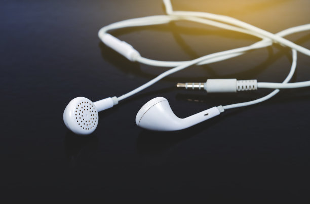 白色耳机背景。现代便携式音频配件。图片下载