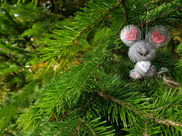 云杉树枝上的圣诞节毛毡装饰。手工制作的象征年岁的小雕像——老鼠。假日背景与副本空间。图片下载