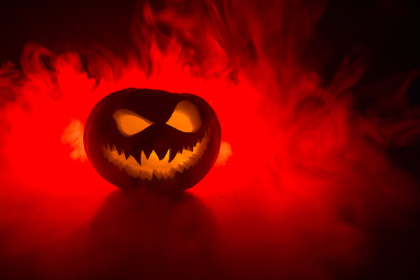 万圣节南瓜微笑和恐怖的眼睛派对之夜。近距离观看可怕的万圣节南瓜与眼睛发光内部在黑色的背景图片下载