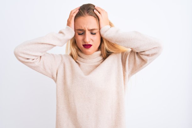 年轻漂亮的女人穿着高领毛衣站在孤立的白色背景下忍受着头痛绝望和压力因为疼痛和偏头痛。手放在头上。图片下载