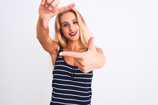 年轻美丽的女人穿着休闲条纹t恤站在孤立的白色背景微笑与手和手指框架与幸福的脸。创意和摄影概念。图片下载