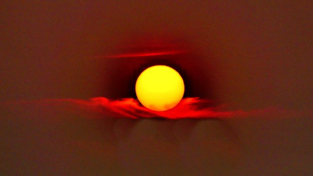 太阳在黑暗的天空中停在一片鲜红的云上图片下载