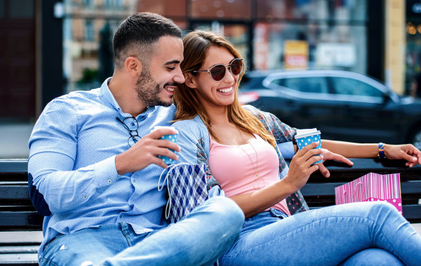 咖啡休息。情侣购物后在公园长椅上休息。消费主义，生活方式，爱情和关系的概念图片下载