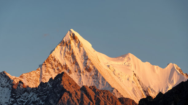 美丽的金色雪山与蓝天背景在日落时间，山顶上的稻城亚丁国家公园，中国，四川。图片下载