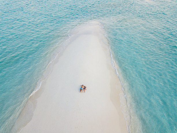 一对年轻的成年夫妇一起躺在马尔代夫碧绿的沙滩上图片下载