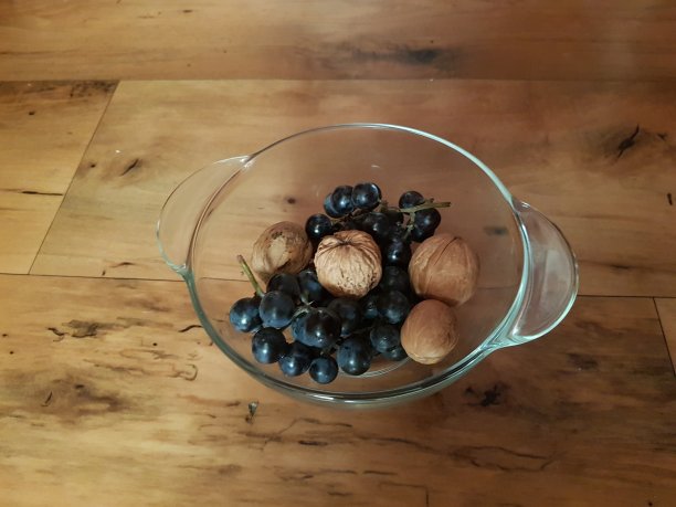 装有蓝色葡萄和坚果的玻璃盘子。图片下载