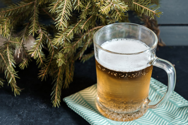 冷杉树枝上的餐巾上放着一杯淡大麦啤酒图片下载