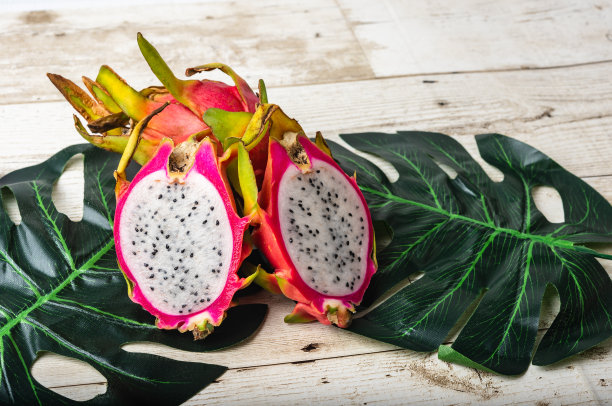 火龙果或火龙果带切片，孤立于观赏叶背景上，食用异域热带营养食品图片下载