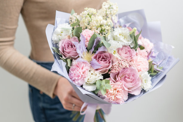 女人手中的混合鲜花花束。花店花艺师作品。柔和的粉色和淡紫色素材图片