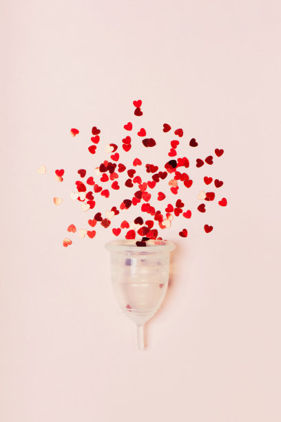 透明的月经杯，红色的心在粉红色的背景图片下载