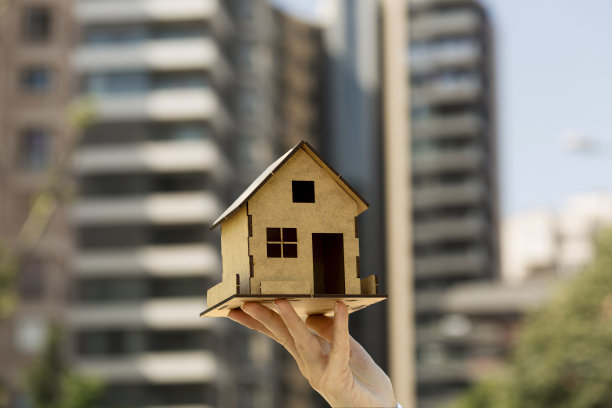女人的手展示房子模型。新房，买和租，抵押，房地产概念。水平的细节特写。图片下载