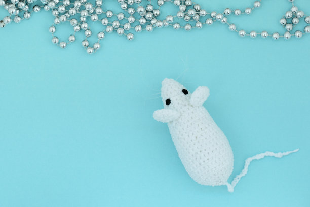 白色钩针老鼠在蓝色背景与银色圣诞装饰。鼠标符号2020年新年。俯视图，复制空间图片下载