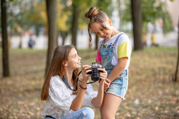街上的两个女孩为互联网制作视频，为相机录制视频博客。有照片的孩子们在城市公园里图片下载