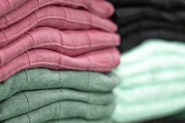 暖和的衣服整齐地叠在货架上。汗衫、毛衣、套头衫、开襟羊毛衫、帽衫、胸围帽都堆在架子上。衣服存储。尺寸范围。图片下载