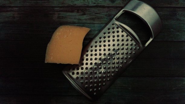 木桌上放着一块奶酪的金属刮刮器图片下载