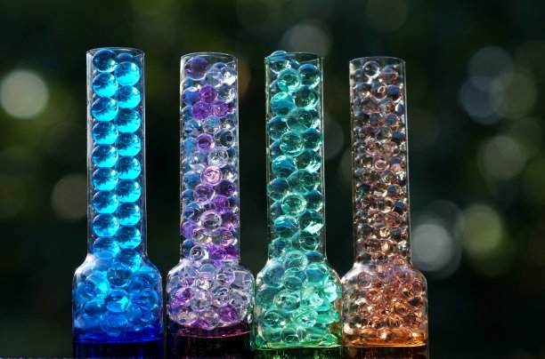 4个不同颜色的玻璃瓶，在绿色的散景背景上充满清晰的气泡图片下载