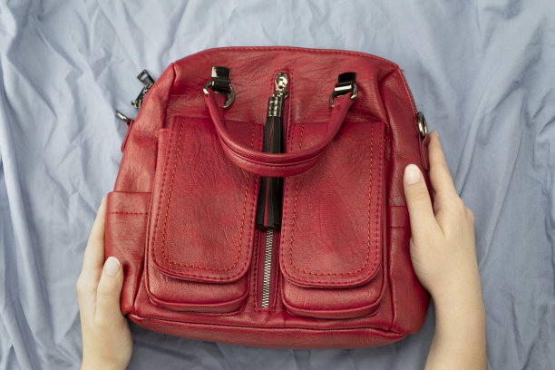 女士手持蓝色底色的红色手提包图片下载