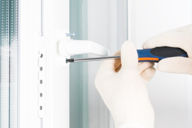 一名工人的手将把手固定在一个塑料窗户上，从侧面可以看到近景图片下载