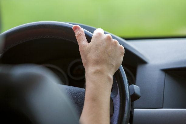 女人开车时双手搭在方向盘上。图片下载