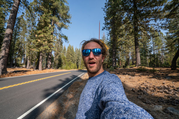 一名年轻人在空旷的高速公路上自拍，靠近黑熊野生动物标志图片下载