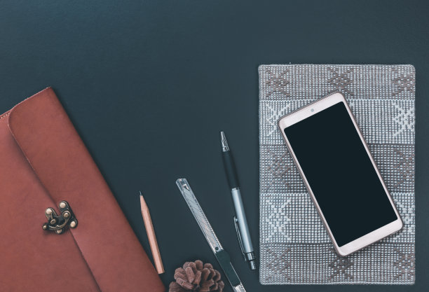 工作空间与手机，皮革bagnotebook，钢笔，铅笔和不锈钢刀具在黑暗的背景，俯视图图片下载