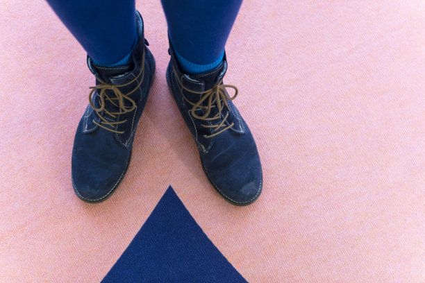 系好鞋带，靴子旁边站着相配的蓝色地毯图案图片下载