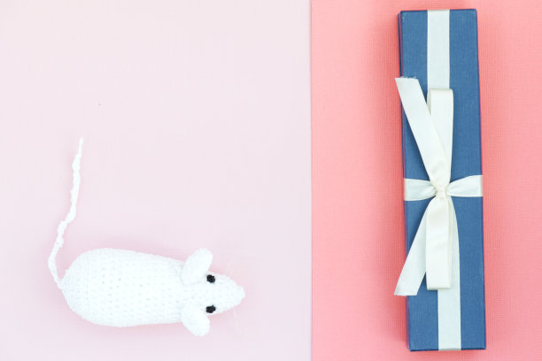 白色钩针老鼠和蓝色礼盒上的纸背景。鼠标符号2020年新年。俯视图，复制空间图片下载