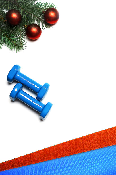 平躺最好的圣诞礼物活跃的人-普拉提瑜伽运动:橙色和蓝色垫子，哑铃和圣诞节装饰。图片下载