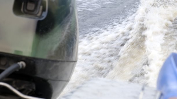 一艘渔船在夕阳下漂浮在河上。从引擎侧看。近距离图片下载