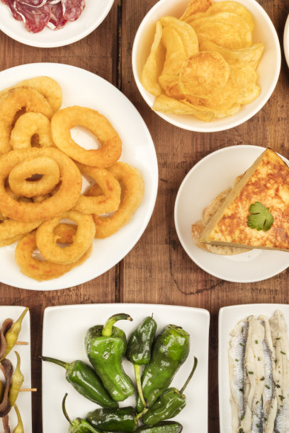 西班牙小吃，各种小吃。鱿鱼圈，玉米饼，沙丁鱼，帕德龙辣椒，上面的照片是在一个黑色的乡村木制背景上，图片下载