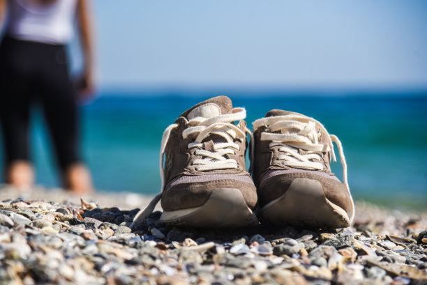 水边沙滩上的运动鞋图片下载