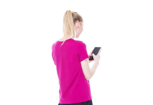 后视图/腰部以上的20-29岁的成年美丽的白人女性/年轻女性在白色背景下运动穿着运动服谁是快乐的/愉快的，拿着手机/使用智能手机/短信图片下载