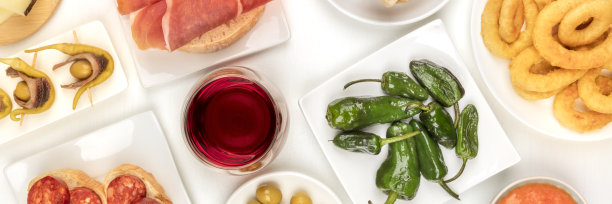 西班牙小吃和葡萄酒，各种小吃的全景照片。帕德隆辣椒，火腿，西班牙香肠，鱿鱼圈，吉尔达斯，在白色的背景下从上面拍摄图片下载