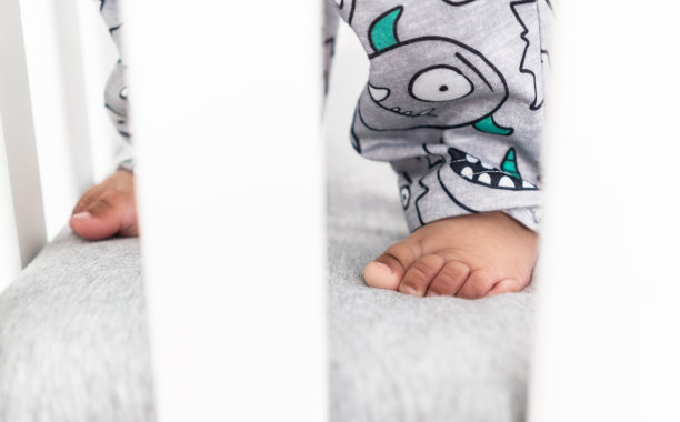 当站在婴儿床上时，近距离观察婴儿的双脚。图片下载