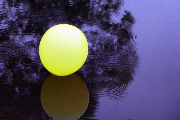 一个孤独的球在黑暗的水中，复制空间。孤独和悲伤的概念——雨中坠落的气球。图片下载