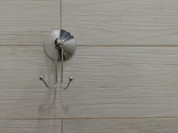 公共厕所的墙上有两个挂钩的金属衣架。图片下载