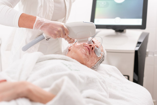 专业设备抗痤疮光疗。美丽的女人在美容院的照片年轻化程序。在美容诊所进行面部激光皮肤治疗。硬件美容图片下载