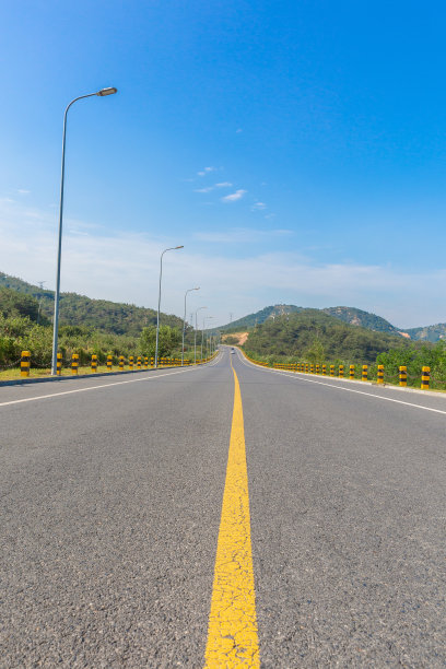 宽阔的道路穿过蓝天白云下的大山图片下载