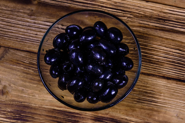 木桌上放着黑橄榄的玻璃碗。俯视图图片下载