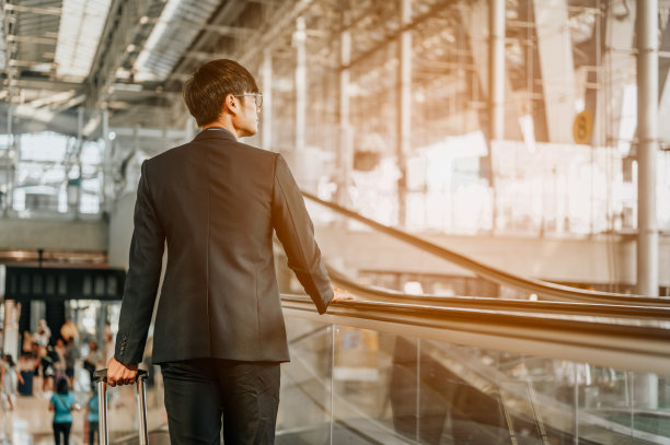 带着手提行李的商人在机场候机楼走来走去。商人提着行李箱走过机场的旅客候机楼。商人，旅行者，旅行，商务旅行。图片下载