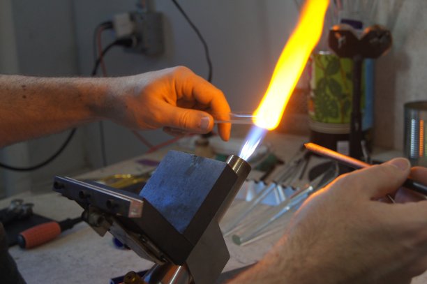 火焰工人熟练地在工作室用火炬加热玻璃图片下载