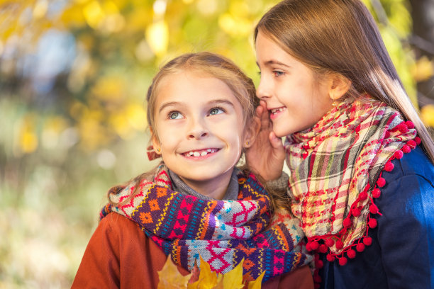 在一个阳光明媚的秋日，两个可爱的8岁女孩在公园里聊天。图片下载