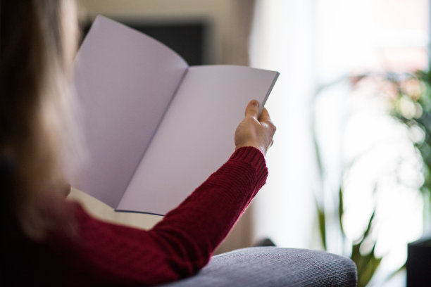 女人阅读空白小册子与副本空间拍摄的背面图片下载