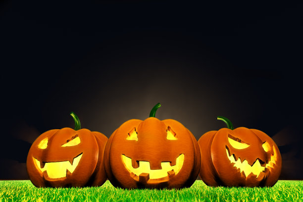 万圣节的南瓜带着鬼脸在草地上伴着夜空图片下载