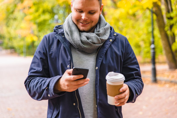 在户外喝咖啡的男人在秋天打电话图片下载