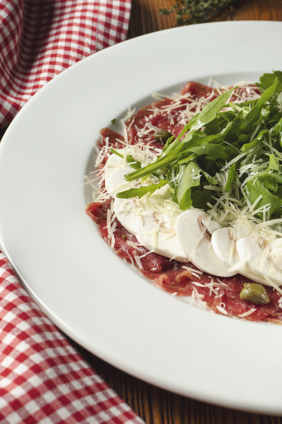 新鲜的小牛肉切片，配芝麻菜和帕尔马干酪蘑菇。关闭视图。意大利菜。食物的照片背景。图片下载