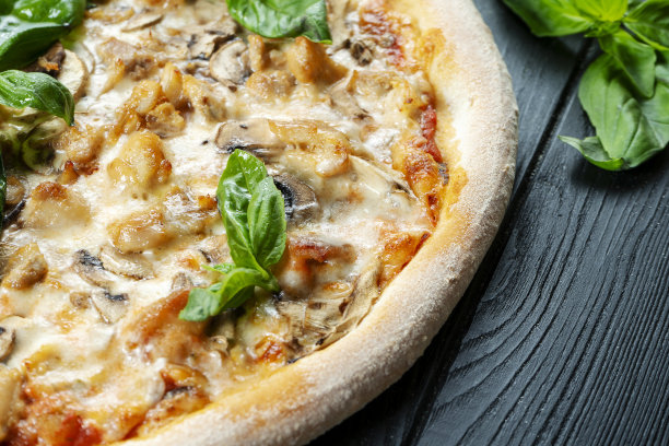 自制的新鲜披萨与烟熏鸡肉，蘑菇，罗勒和白酱在一个黑色的木头复制空间。俯视图食物照片。平的。意大利菜。图片下载
