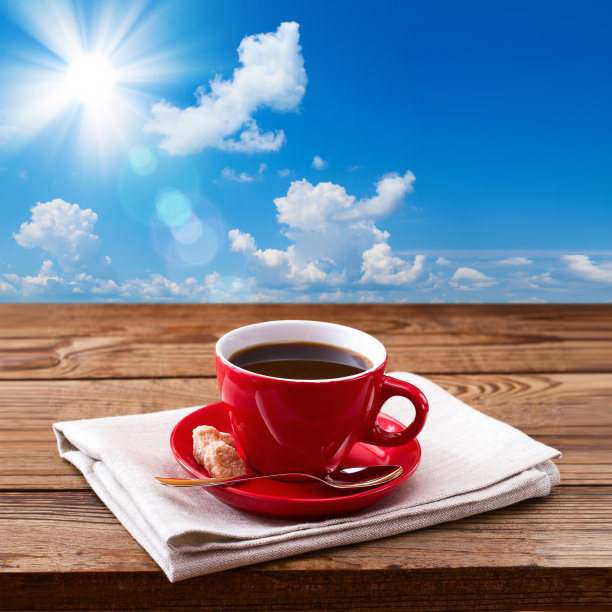 红杯可口的咖啡放在餐巾纸上，放在木桌上。秋天背景图片下载