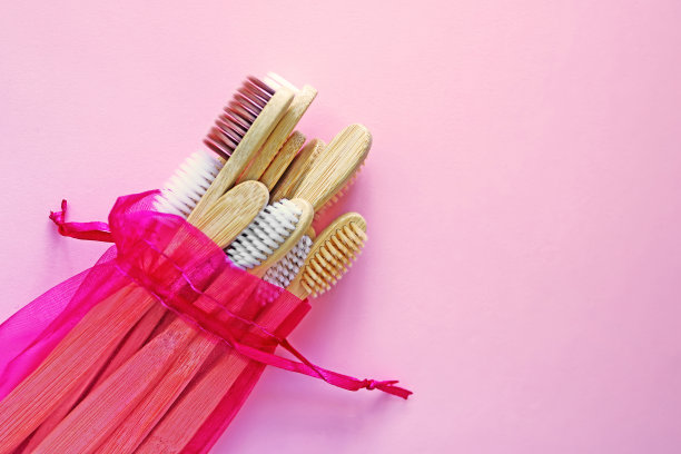深红色袋装竹牙刷，可重复使用，背景是时尚的粉红色。环保产品。生态、零浪费和健康理念。平的。文本。生物可降解材料图片下载