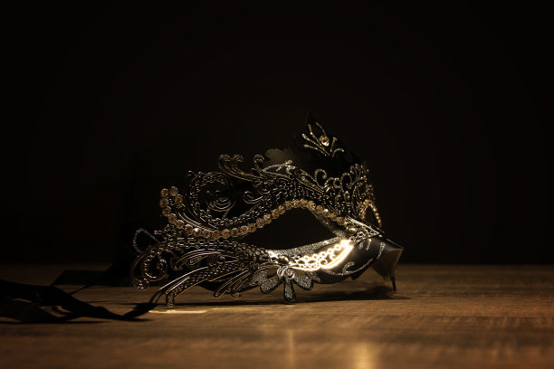神秘的面具。一张威尼斯面具的肖像放在一张被黑暗包围的木桌上。图片下载